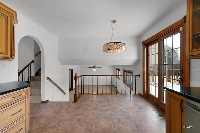 tiled entrance foyer with arched walkways, visible vents, stairs, and baseboards