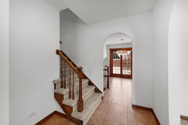 tiled foyer entrance with stairway, arched walkways, and baseboards