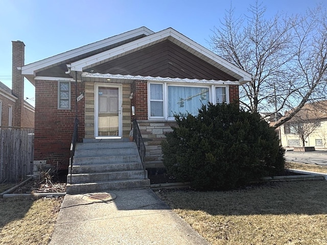 view of front of house with brick siding, stone siding, and fence