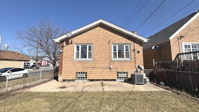 rear view of house featuring brick siding, central air condition unit, a yard, and a fenced backyard