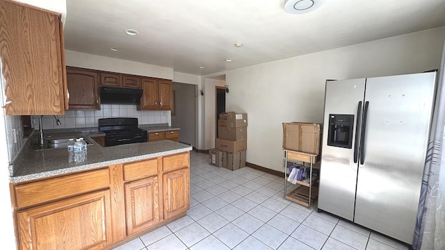 kitchen featuring a sink, stainless steel refrigerator with ice dispenser, black range with gas stovetop, under cabinet range hood, and tasteful backsplash