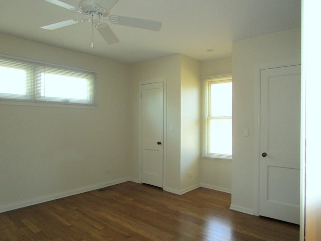 unfurnished bedroom with baseboards, multiple windows, wood finished floors, and a ceiling fan