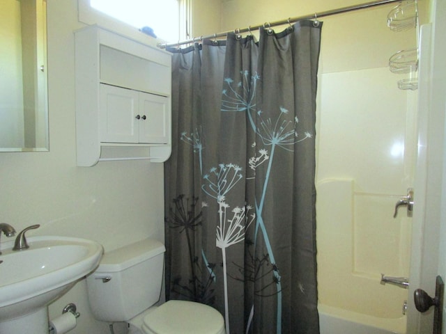 bathroom with toilet, shower / bath combo with shower curtain, and a sink