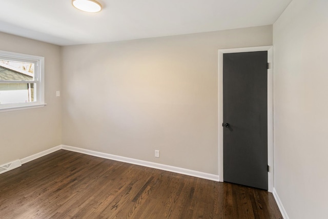 empty room featuring visible vents, baseboards, and dark wood-type flooring