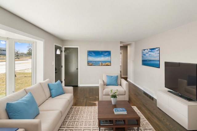 living area with dark wood finished floors, baseboards, and visible vents