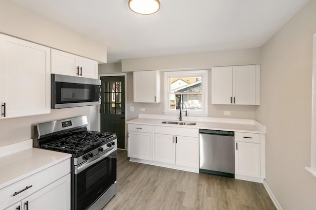 kitchen featuring a sink, light countertops, white cabinets, appliances with stainless steel finishes, and light wood-type flooring