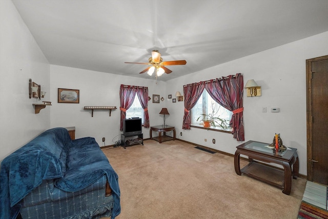 living room with ceiling fan, baseboards, visible vents, and light carpet