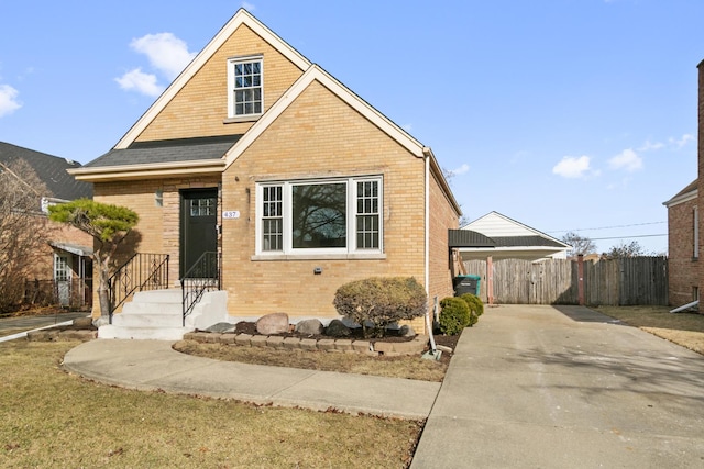 bungalow-style house with concrete driveway, fence, and brick siding