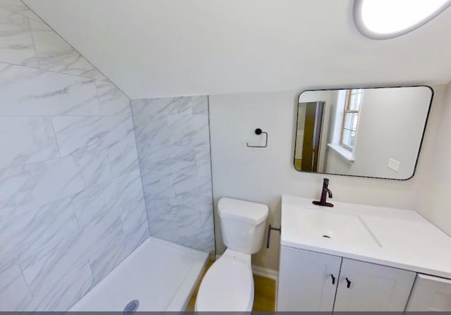 bathroom featuring a tile shower, toilet, and vanity