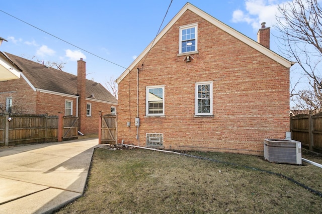 rear view of property with cooling unit, brick siding, a chimney, and fence