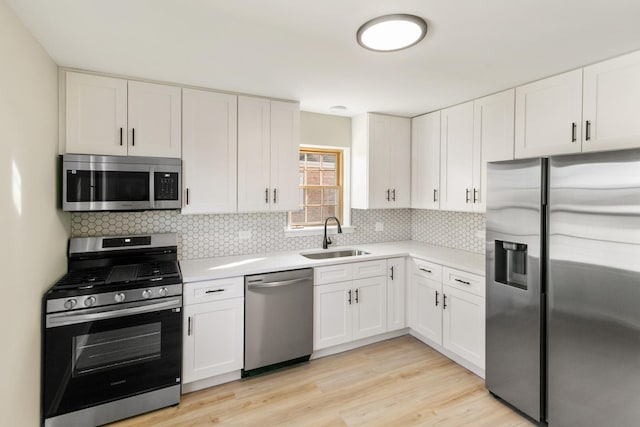 kitchen featuring light countertops, decorative backsplash, appliances with stainless steel finishes, white cabinetry, and a sink