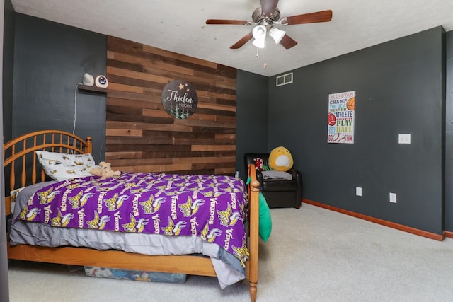 carpeted bedroom with visible vents, baseboards, wooden walls, and an accent wall