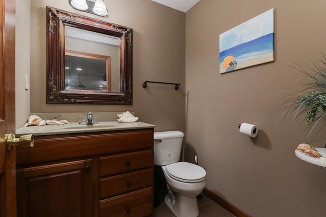 bathroom featuring toilet, vanity, and baseboards