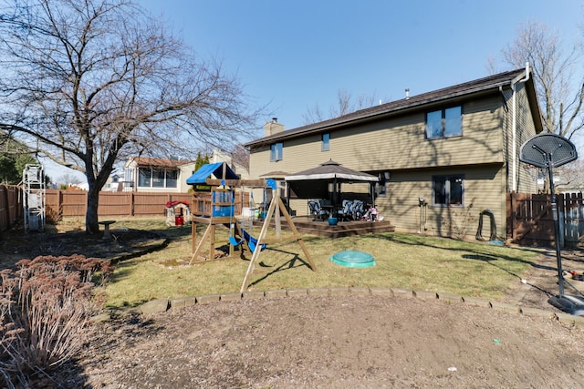 rear view of property featuring a fenced backyard, a playground, a gazebo, a yard, and a chimney