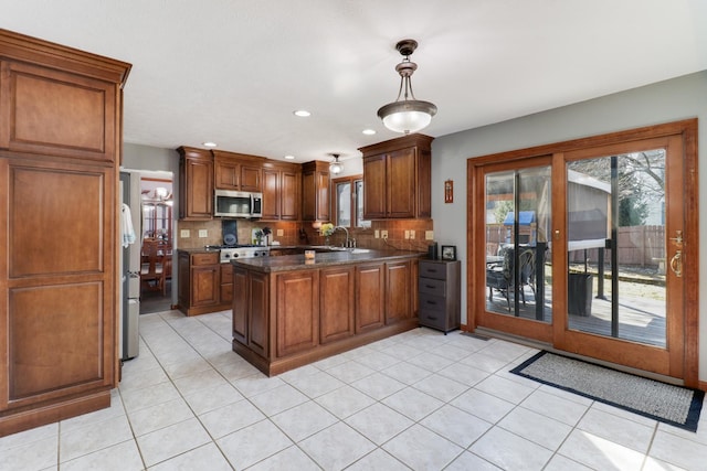 kitchen with decorative backsplash, a healthy amount of sunlight, appliances with stainless steel finishes, and a peninsula