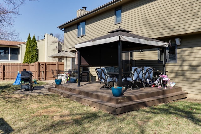 back of house with a lawn, fence, a gazebo, a wooden deck, and a chimney