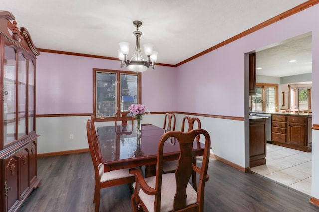 dining area with light wood finished floors, a notable chandelier, crown molding, and baseboards