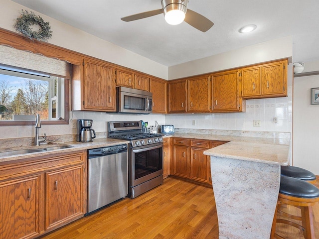 kitchen featuring a sink, stainless steel appliances, brown cabinets, and a kitchen breakfast bar