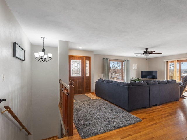 living area featuring a healthy amount of sunlight, wood finished floors, and ceiling fan with notable chandelier