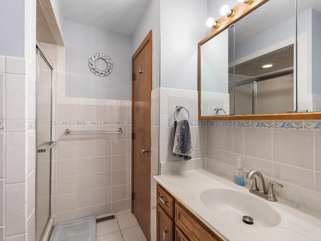 bathroom with tile patterned floors, visible vents, a stall shower, tile walls, and vanity