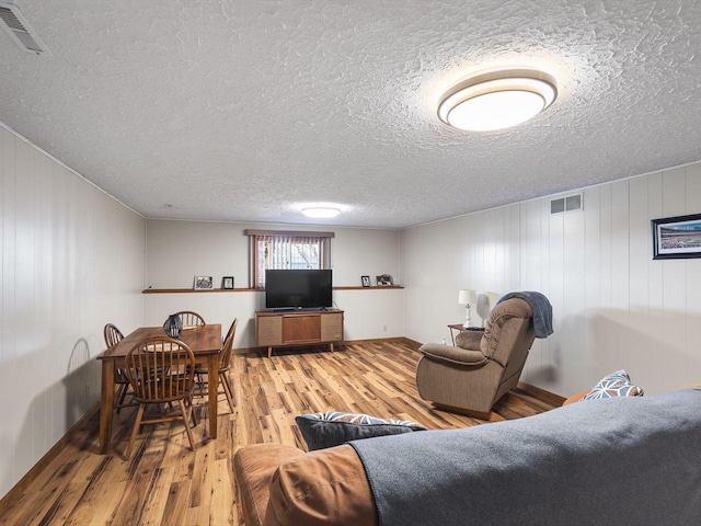 living room with visible vents, a textured ceiling, and wood finished floors