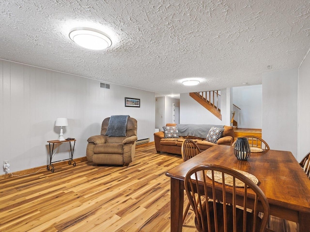 living room with stairway, visible vents, light wood finished floors, a textured ceiling, and baseboard heating