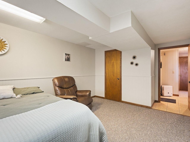 bedroom with a wainscoted wall and light carpet