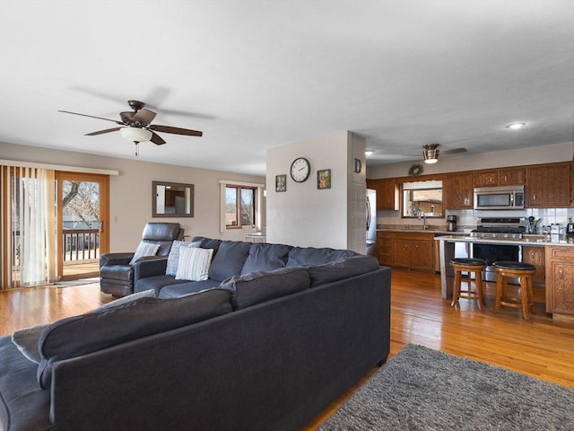 living area with recessed lighting, a healthy amount of sunlight, a ceiling fan, and light wood-style floors