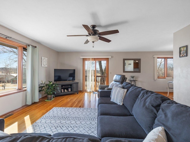 living area featuring a healthy amount of sunlight, ceiling fan, and wood finished floors