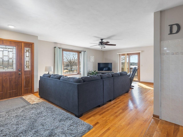 living area with light wood finished floors, baseboards, and a ceiling fan