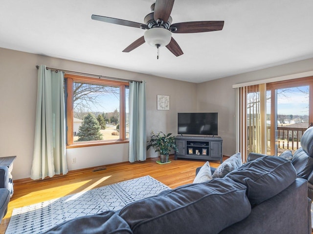 living room with wood finished floors, visible vents, a wealth of natural light, and ceiling fan