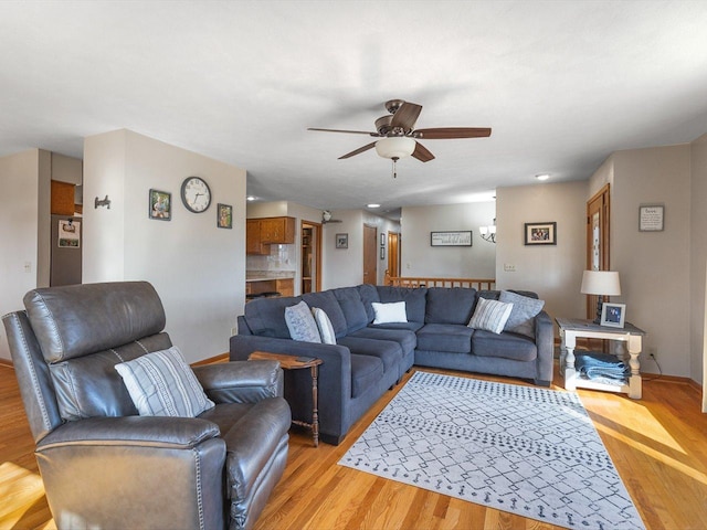 living area featuring light wood-style flooring, a ceiling fan, and baseboards