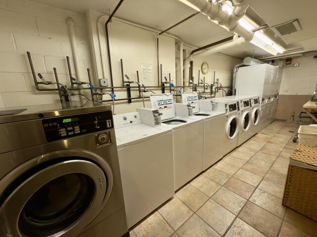 common laundry area featuring concrete block wall, visible vents, and independent washer and dryer