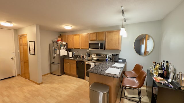 kitchen featuring a breakfast bar, a peninsula, light wood-style floors, stainless steel appliances, and a sink