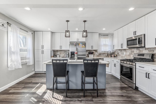 kitchen with a sink, dark wood-type flooring, appliances with stainless steel finishes, and a center island