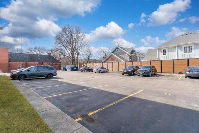 uncovered parking lot featuring a residential view and fence