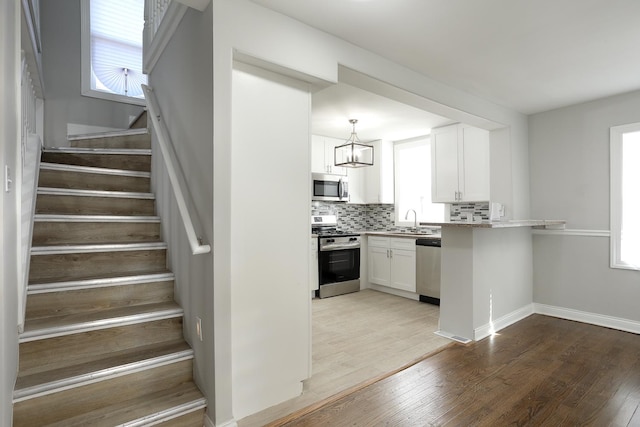 kitchen featuring backsplash, appliances with stainless steel finishes, light wood-type flooring, and a sink