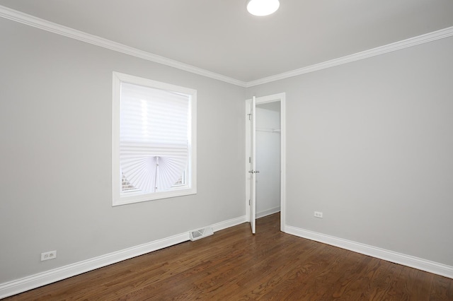 unfurnished room with visible vents, baseboards, dark wood-style floors, and crown molding