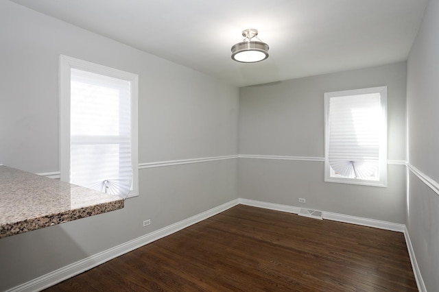 unfurnished room with dark wood-type flooring, baseboards, and visible vents