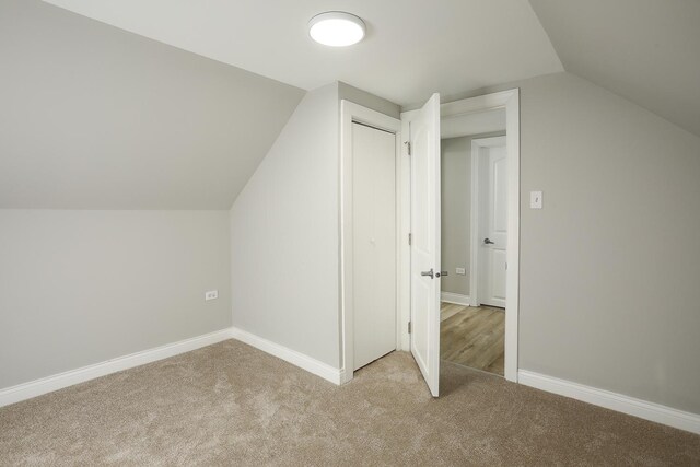 additional living space with baseboards, lofted ceiling, and carpet flooring