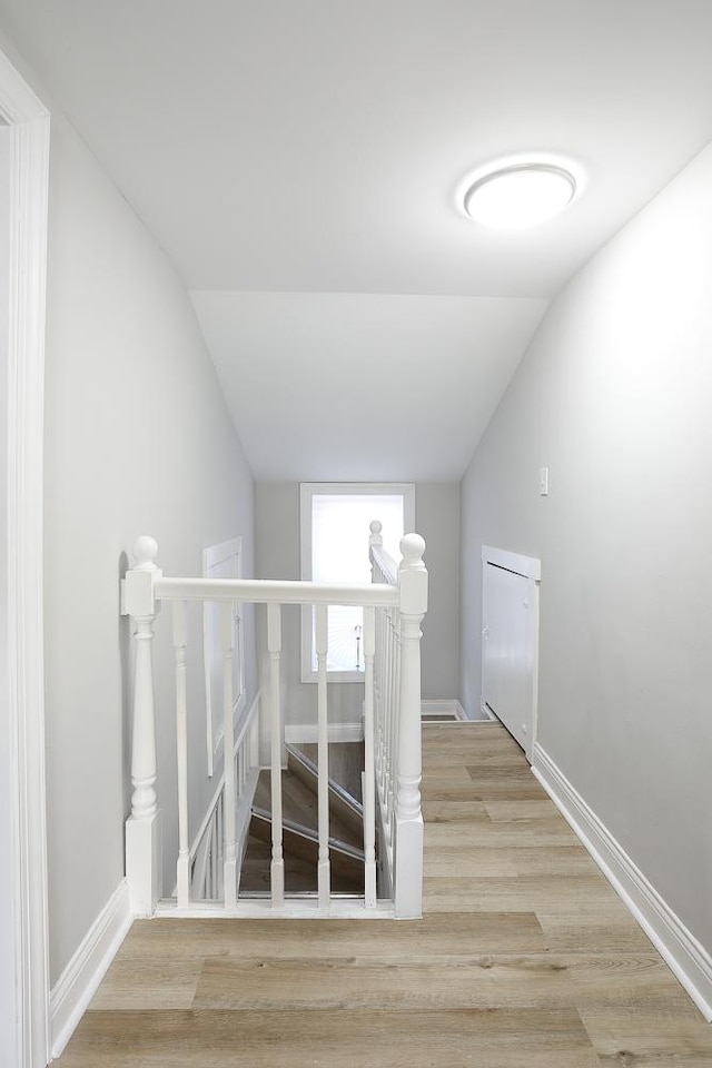 staircase with vaulted ceiling, wood finished floors, and baseboards