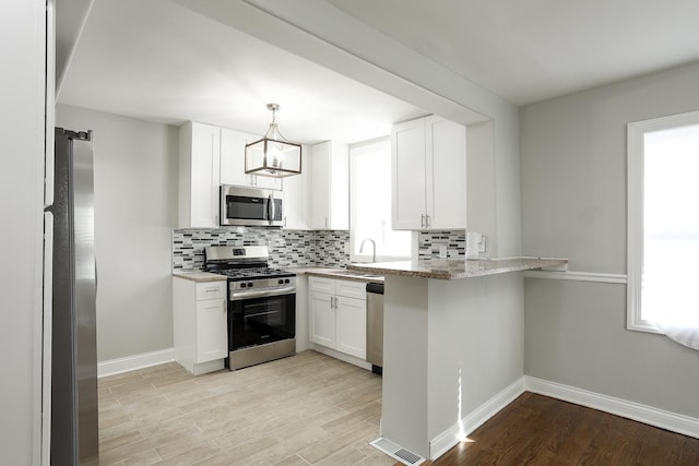 kitchen featuring visible vents, appliances with stainless steel finishes, decorative backsplash, and light wood finished floors