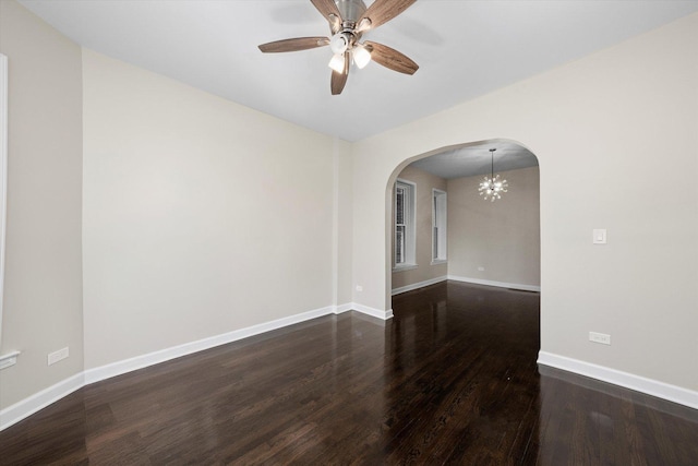 unfurnished room with arched walkways, ceiling fan with notable chandelier, baseboards, and wood finished floors