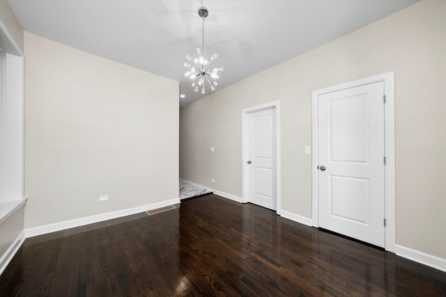 unfurnished room featuring dark wood-style floors, baseboards, and a chandelier