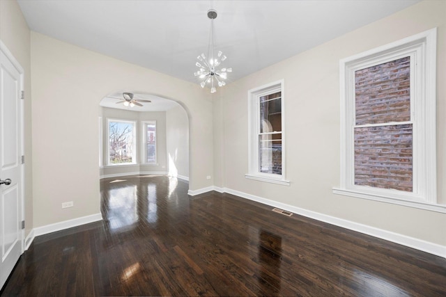 unfurnished dining area with a notable chandelier, dark wood-style floors, arched walkways, and baseboards