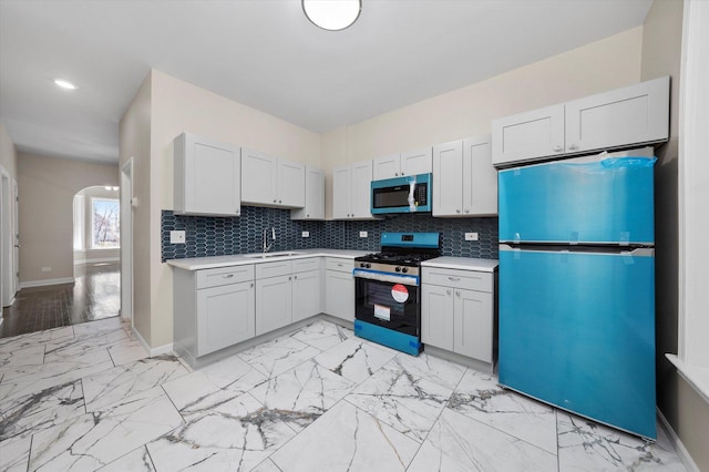 kitchen with a sink, marble finish floor, tasteful backsplash, and appliances with stainless steel finishes