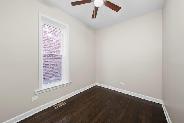 empty room with dark wood-style floors, visible vents, and baseboards