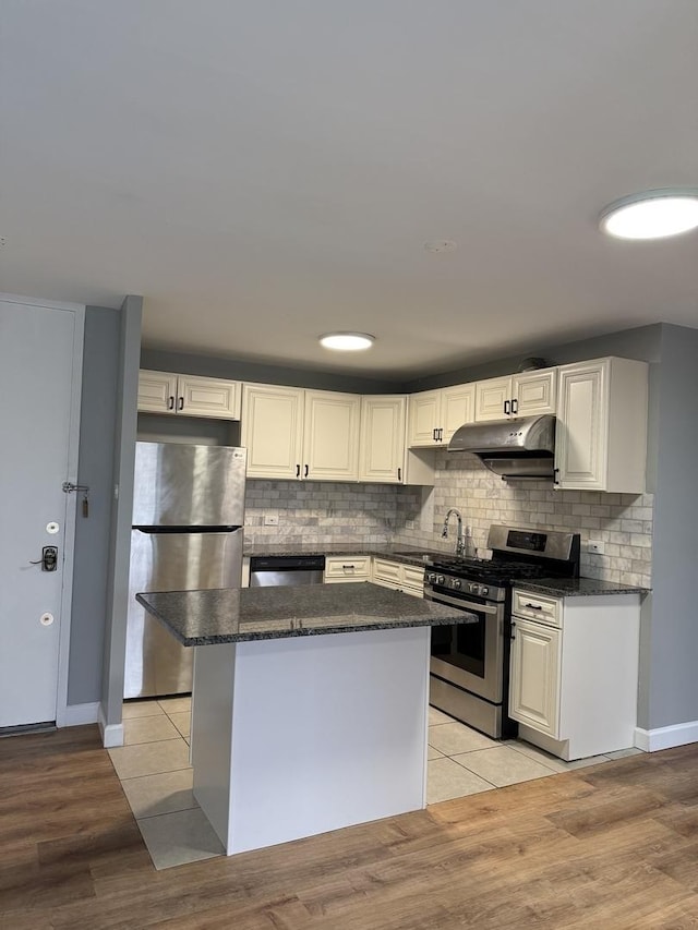 kitchen with under cabinet range hood, a kitchen island, backsplash, and stainless steel appliances