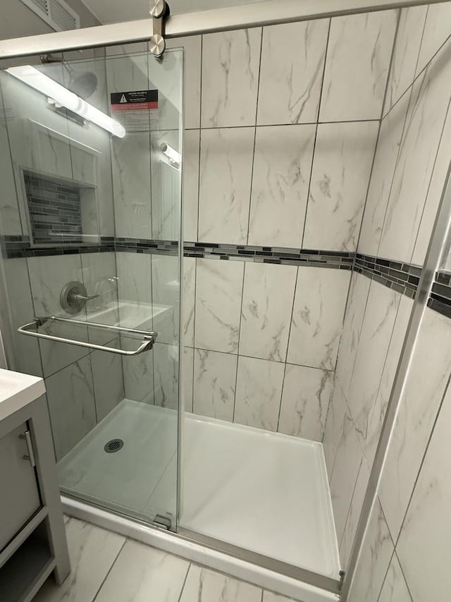 full bath featuring marble finish floor, a stall shower, and vanity