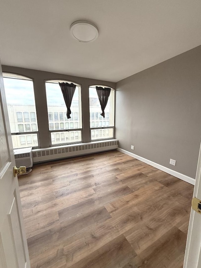 spare room featuring wood finished floors, baseboards, and baseboard heating